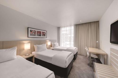 Habitación de hotel con 2 camas y escritorio en Travelodge Hotel Melbourne Docklands en Melbourne