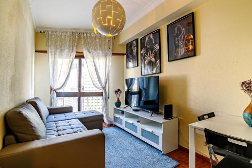ein Wohnzimmer mit einem Sofa und einem TV in der Unterkunft Porto Central Home in Porto