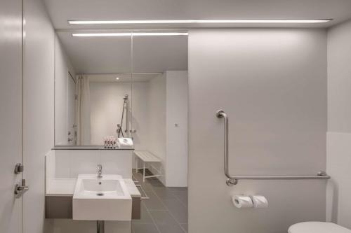 a bathroom with a sink and a toilet and a mirror at Travelodge Hotel Melbourne Docklands in Melbourne