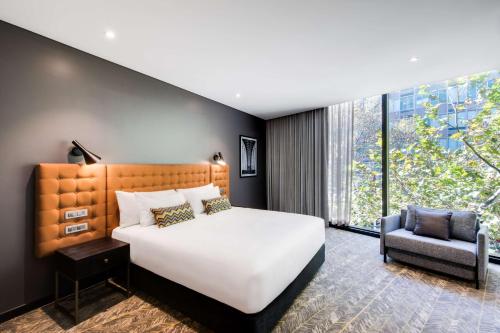 a bedroom with a large bed and a chair at Vibe Hotel North Sydney in Sydney