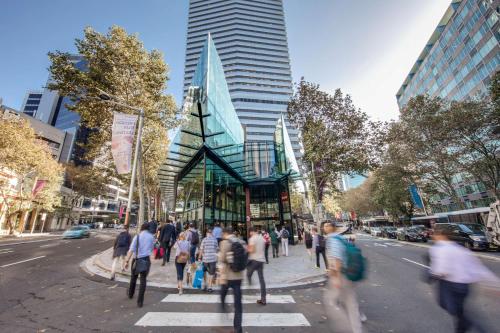 a group of people crossing a street in front of a building at Vibe Hotel North Sydney in Sydney