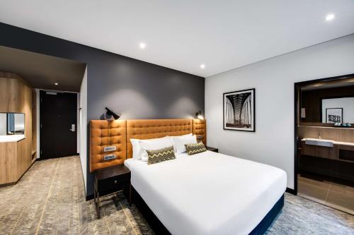 a bedroom with a large white bed and a bathroom at Vibe Hotel North Sydney in Sydney