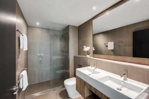 a bathroom with a sink and a toilet and a mirror at Vibe Hotel North Sydney in Sydney