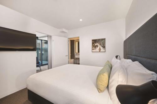 a bedroom with a large white bed with a black headboard at Vibe Hotel Melbourne in Melbourne