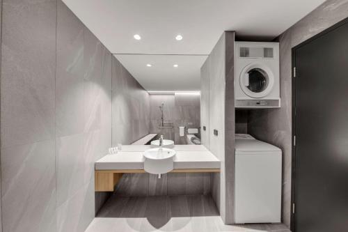 uma casa de banho com um lavatório e uma máquina de lavar roupa em Vibe Hotel Hobart em Hobart