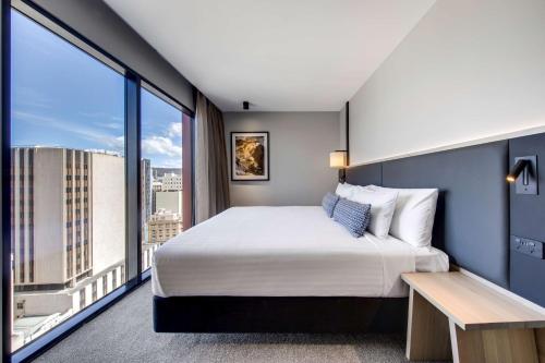 a hotel room with a bed and a large window at Vibe Hotel Hobart in Hobart