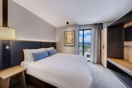 a bedroom with a large white bed and a window at Vibe Hotel Hobart in Hobart