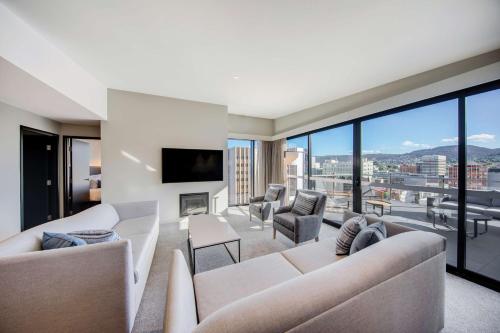 a living room with white furniture and a large window at Vibe Hotel Hobart in Hobart