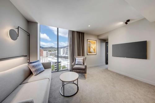 a living room with a couch and a flat screen tv at Vibe Hotel Hobart in Hobart