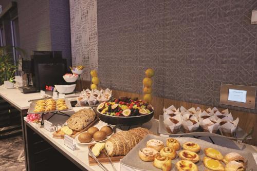 a buffet line with different types of bread and pastries at Travelodge Hotel Hurstville Sydney in Sydney