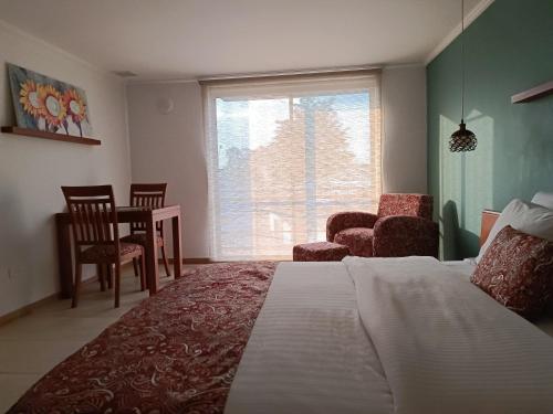 a bedroom with a bed and a chair and a window at Hotel Boutique Confort Suites in Popayan