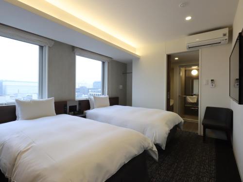 Habitación de hotel con 2 camas y ventana en HOTEL M's EST KYOTO STATION SOUTH en Kioto