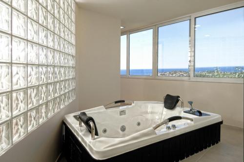 eine Badewanne im Bad mit 2 Fenstern in der Unterkunft Mistral Mare Hotel in Istro