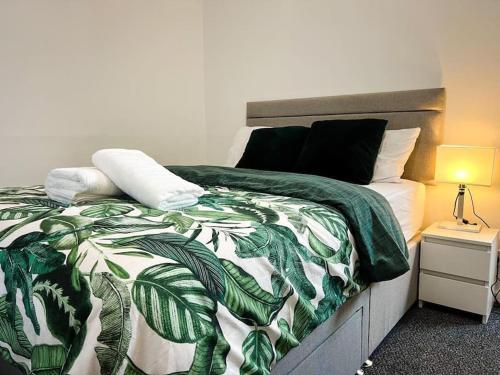 ein Schlafzimmer mit einem Bett mit einer grünen und weißen Decke in der Unterkunft Adorable 2 bed house ideal for Family of Four in Manchester