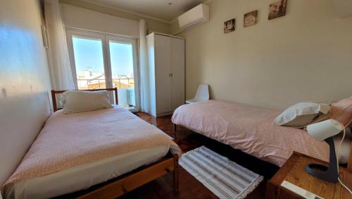 um pequeno quarto com 2 camas e uma janela em Oeiras Historic Bedrooms em Oeiras