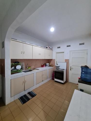 uma grande cozinha com armários brancos e um frigorífico em The Forest Villa em Bogor