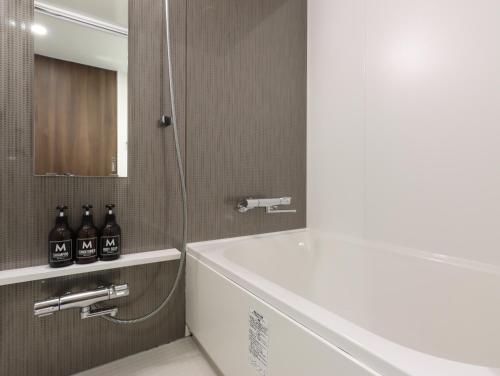 a bathroom with a white tub and a sink and a mirror at HOTEL M's EST KYOTO STATION SOUTH in Kyoto