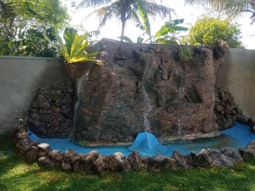 a waterfall in a rock in a yard at White House Family Stay in Maspota