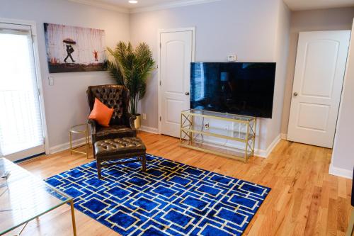 a living room with a tv and a chair and a blue rug at Amazing ATL downtown houses - minutes walk to bars, food and transport! in Atlanta