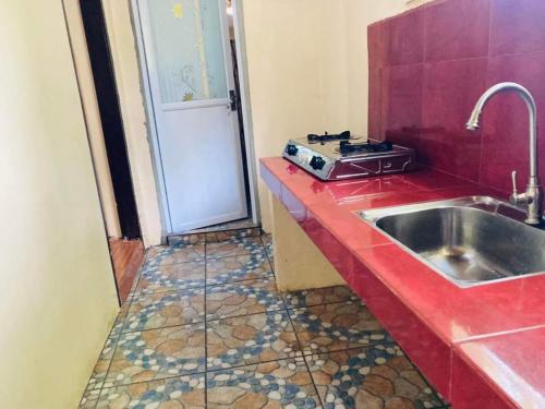a kitchen with a sink and a red counter top at Jeremias Transient Patar Bolinao near WhiteBeach LightHouse in Bolinao