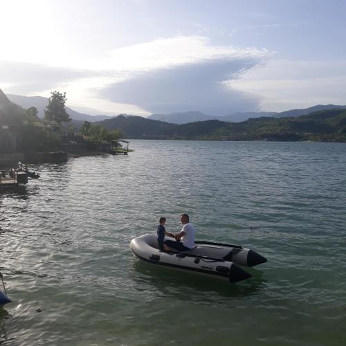 a man and a child sitting on a boat on a lake at Lejla apartmani - Jablaničko jezero in Konjic