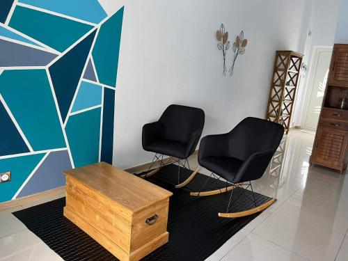 two black chairs and a table in a room at Le Pavillon du trou d'eau in La Saline les Bains