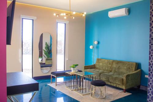 a living room with a couch and a blue wall at Catrina Valle - Ubicación 10 in Valle de Guadalupe