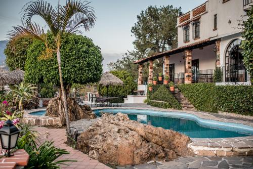 a house with a swimming pool and a palm tree at Hotel Cielito Lindo, Taxco in Taxco de Alarcón