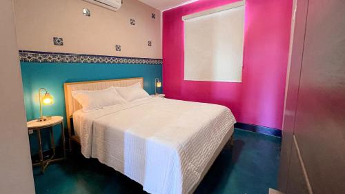 a bedroom with a white bed and a pink wall at Catrina Valle - Ubicación 10 in Valle de Guadalupe
