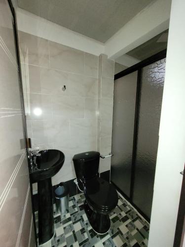 a bathroom with a black toilet and a sink at ALOJAMIENTOS GLORIA in Doradal