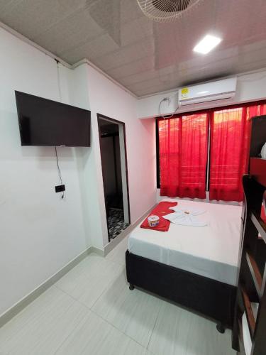 a bedroom with a bed with red curtains and a tv at ALOJAMIENTOS GLORIA in Doradal