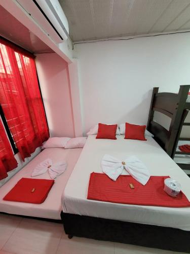 two beds in a room with red and white sheets at ALOJAMIENTOS GLORIA in Doradal