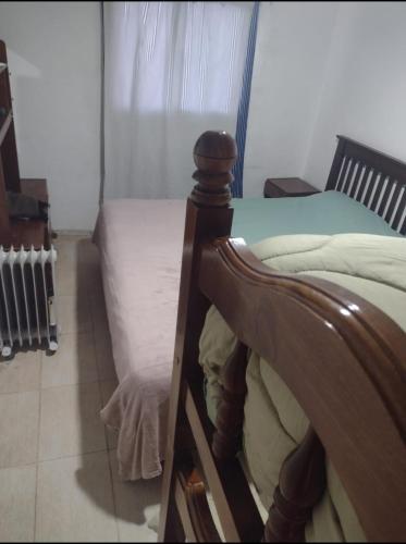 1 cama con marco de madera en una habitación en Tu descanso san Luis en San Luis