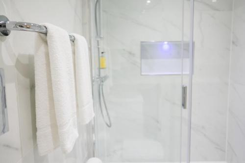 a bathroom with a shower with white towels at Best Western Buckingham Palace Rd in London