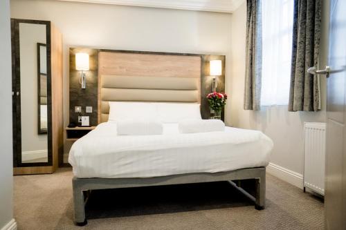 a bedroom with a large white bed and a mirror at Best Western Buckingham Palace Rd in London