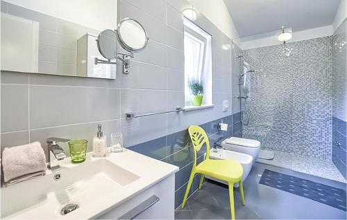 a bathroom with a sink and a yellow chair at Lovely Home In Snasici With Sauna in Mali Turini