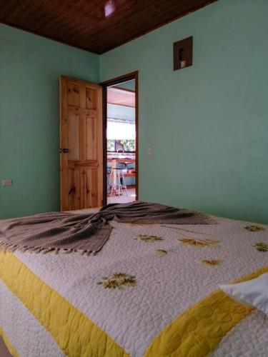 1 dormitorio con 1 cama grande con manta blanca y amarilla en Casa Beli, en Monteverde