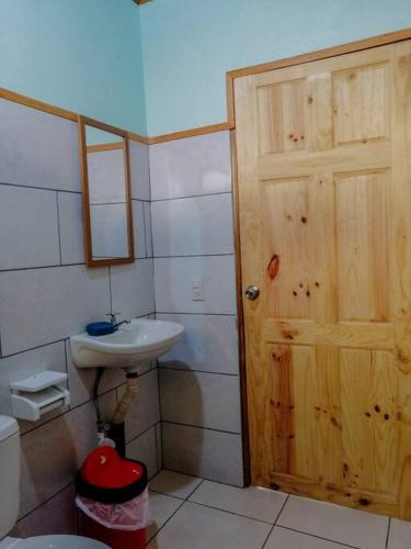 baño con lavabo y puerta de madera en Casa Beli, en Monteverde