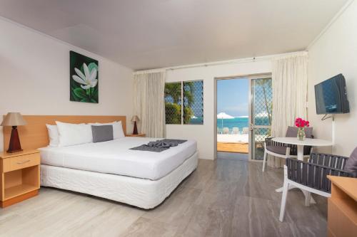 Schlafzimmer mit einem Bett, einem Tisch und einem Fenster in der Unterkunft Moana Sands Beachfront Hotel in Rarotonga