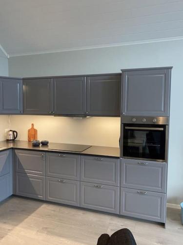 a kitchen with gray cabinets and a microwave at Helt ny rorbu på Slyngstad i Ålesund Kommune in Ålesund