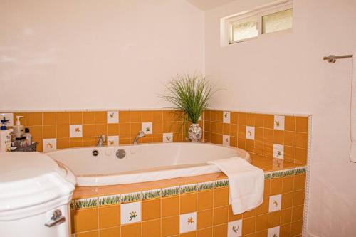 La salle de bains est pourvue d'une baignoire et de carrelage orange. dans l'établissement The Enchanted Garden Retreat: Near Disneyland & More!, à Fullerton
