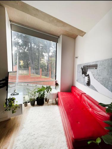 un sofá rojo en una sala de estar con una gran ventana en Hermoso Apartamento en el Mejor Barrio de Bogotá, en Bogotá