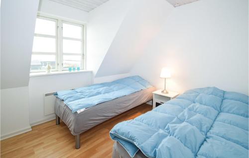 1 dormitorio con 2 camas con sábanas azules y ventana en Awesome Apartment In Karrebksminde With Wifi, en Karrebæksminde
