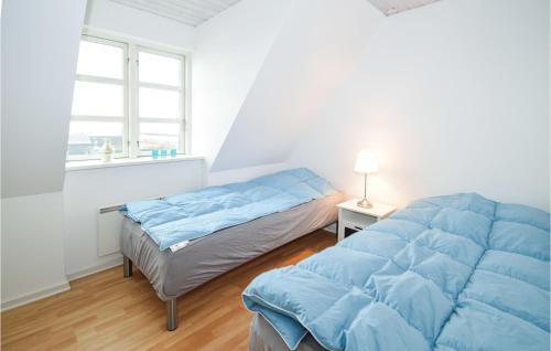 1 dormitorio con 2 camas con sábanas azules y ventana en Amazing Apartment In Karrebksminde With 3 Bedrooms And Wifi en Karrebæksminde