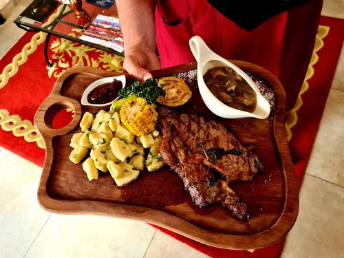 a plate of food with meat and vegetables on a cutting board at Hotel & Restoran Dvorac Gjalski in Zabok
