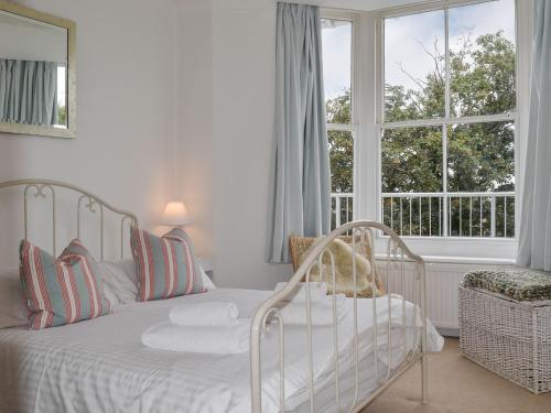 a white bedroom with a bed and a window at Caerleon in Salcombe