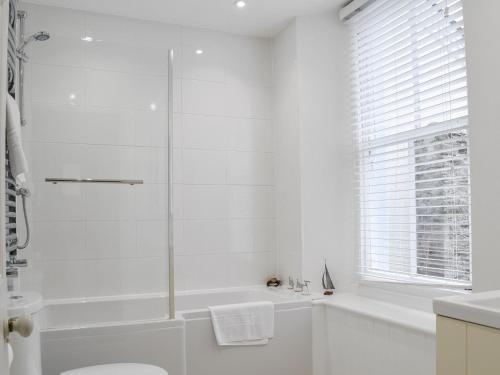 uma casa de banho branca com uma banheira e um chuveiro em Caerleon em Salcombe