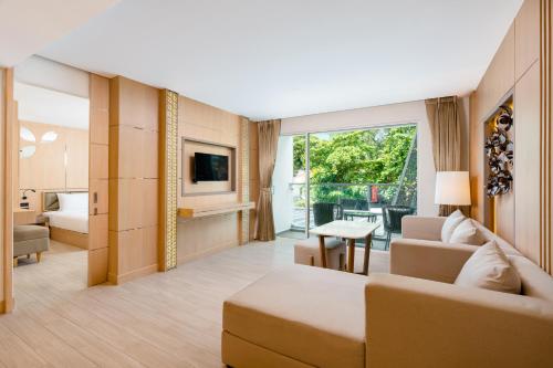 Clarian Hotel Beach Patong في شاطيء باتونغ: غرفة معيشة مع أريكة وسرير وتلفزيون