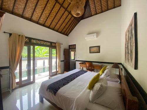 a bedroom with a bed and a large window at Agung Village in Tanah Lot