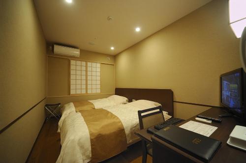a bedroom with a bed and a desk with a computer at Tokyo Yugawara Onsen Manyo no Yu in Machida